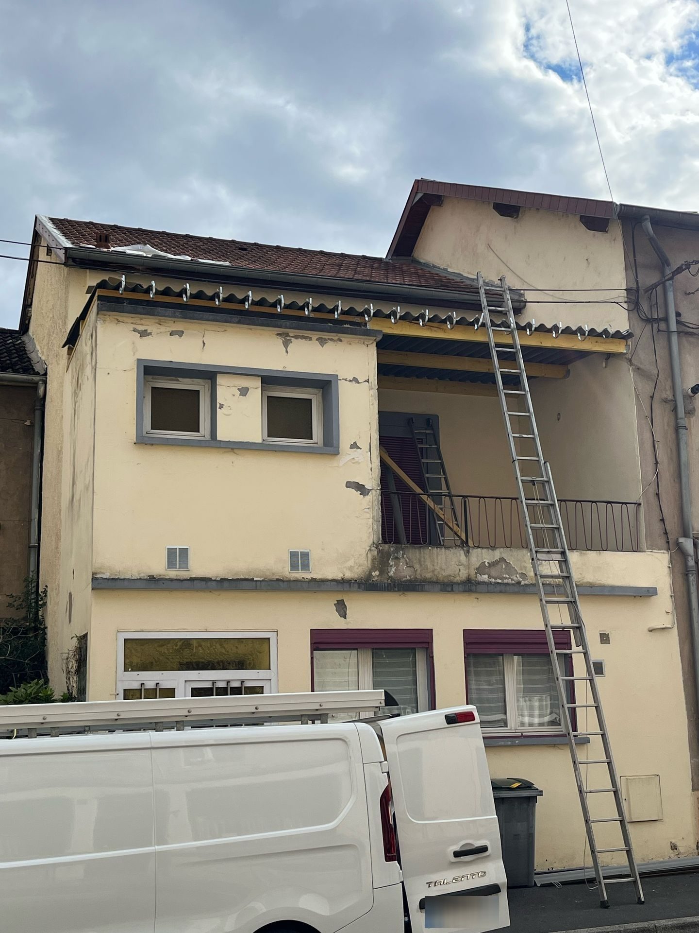 Façade avec échelle posée jusqu'au bord du toit et camionnette